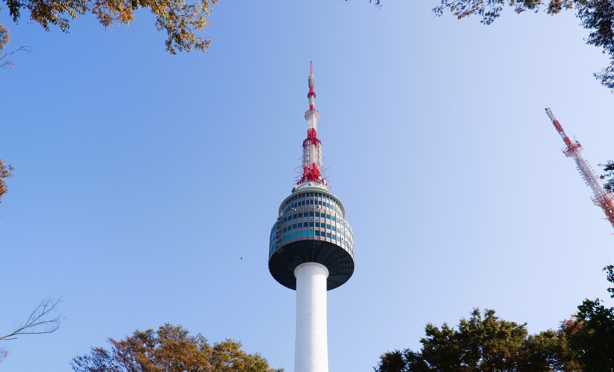 Menara N Seoul Tower menjulang dengan langit biru cerah dan dedaunan musim gugur