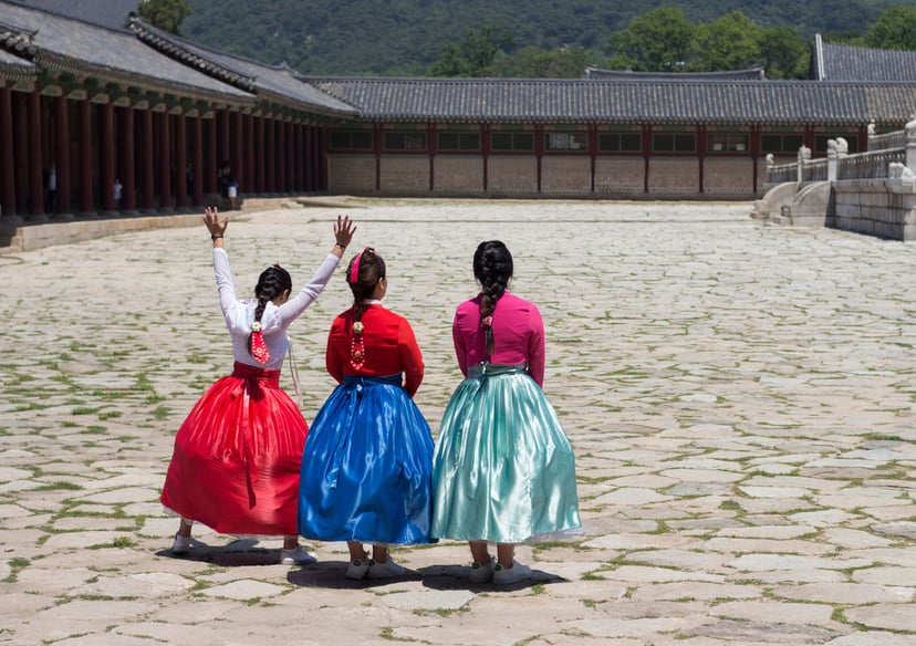 Perempuan berhanbok putih berjalan di halaman istana dengan pohon ginkgo kuning musim gugur, Seoul