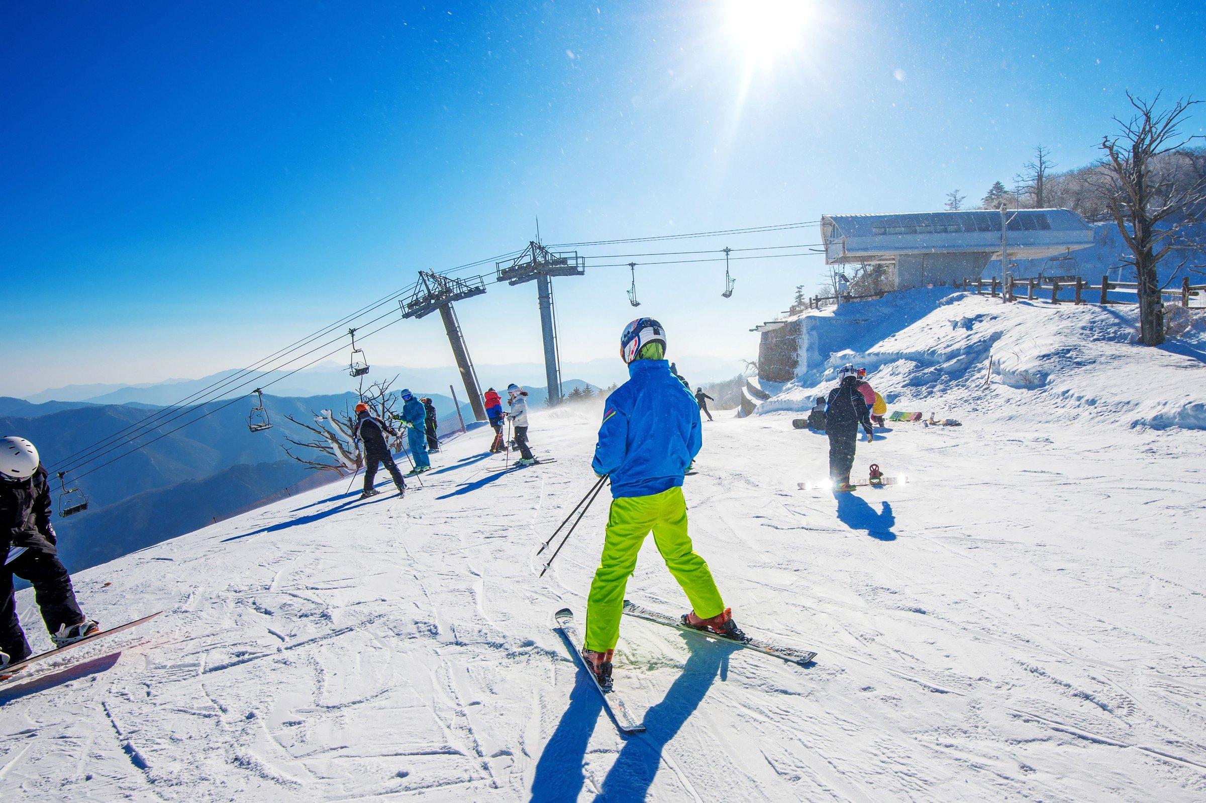 Pemain ski menuruni lereng resor ski Korea dengan kursi gantung dan pegunungan bersalju di latar