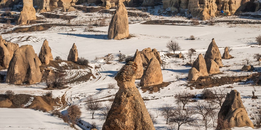 Formasi batu Love Valley, Cappadocia, bersalju dengan cahaya matahari terbit hangat