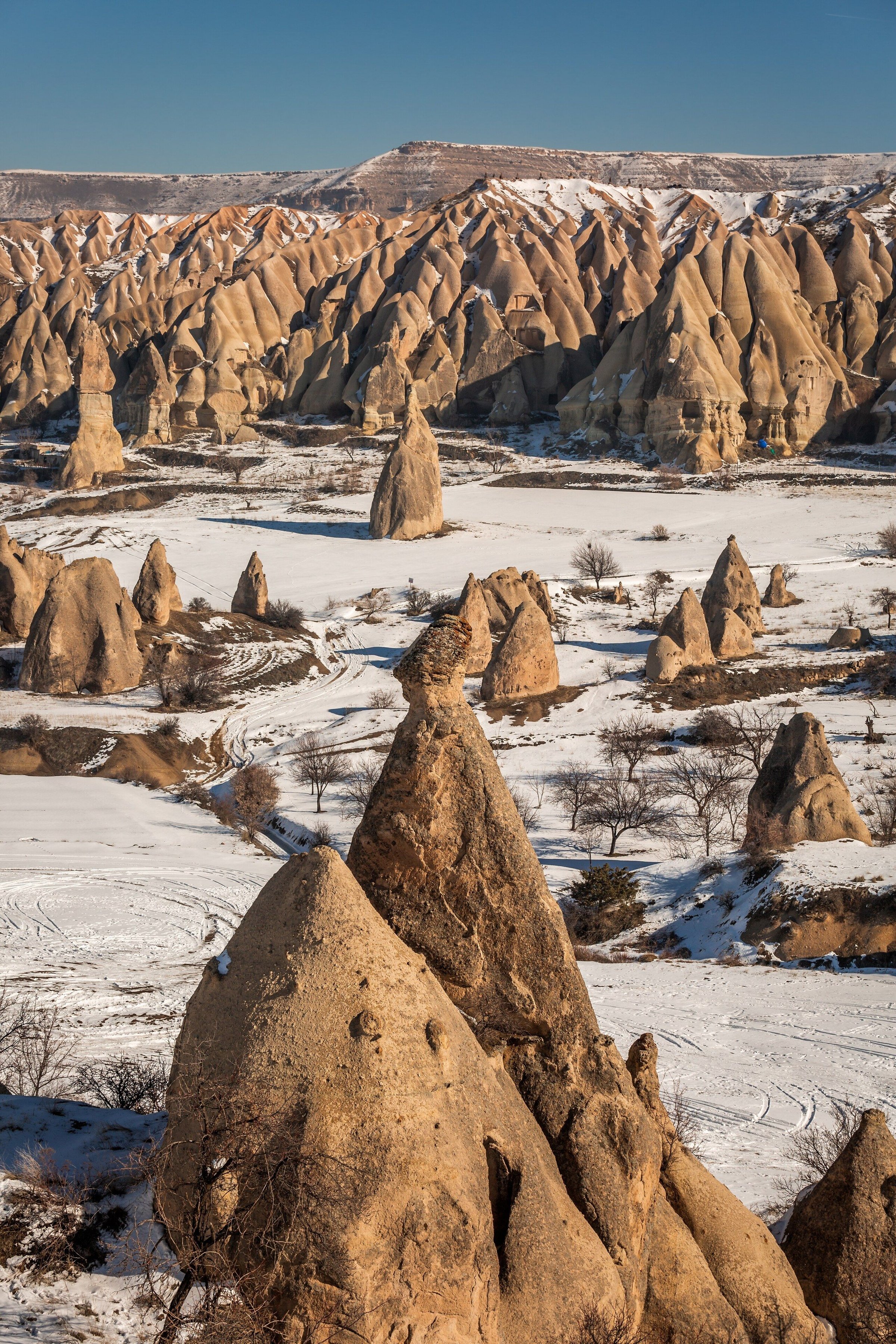Formasi batu Love Valley, Cappadocia, bersalju dengan cahaya matahari terbit hangat