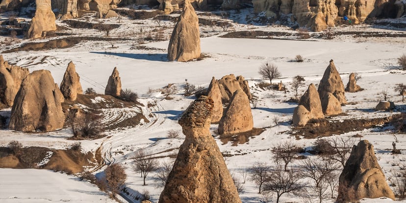 Formasi batu Love Valley, Cappadocia, bersalju dengan cahaya matahari terbit hangat