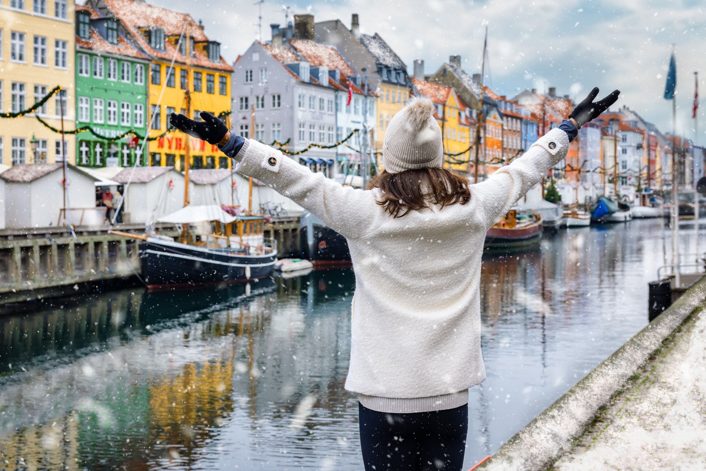 Wisatawan membentangkan tangan di tepi kanal Nyhavn Kopenhagen