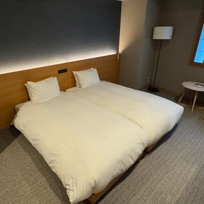 The main bedroom of the Two Bedroom Theater Suite has two twin beds, Japanese style-window covering, flatscreen TV on the wall and a closet.
