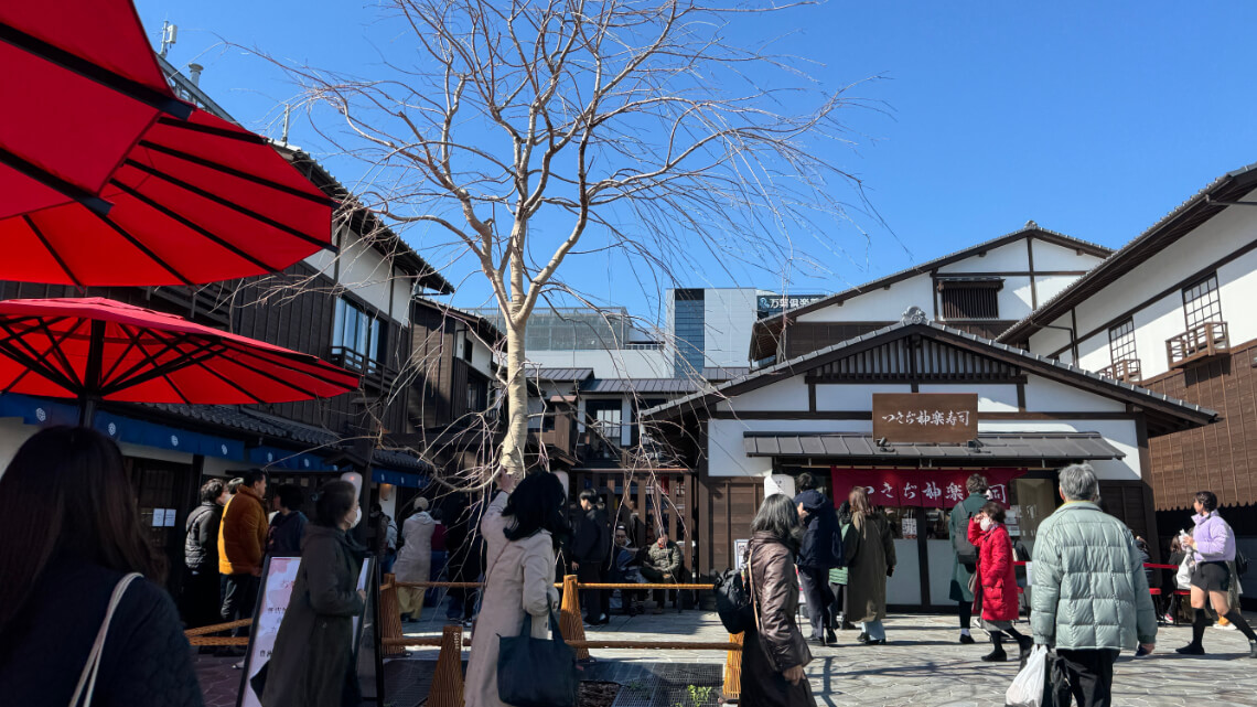 A lively courtyard at Toyosu Senkyaku Banrai, surrounded by traditional wooden buildings.