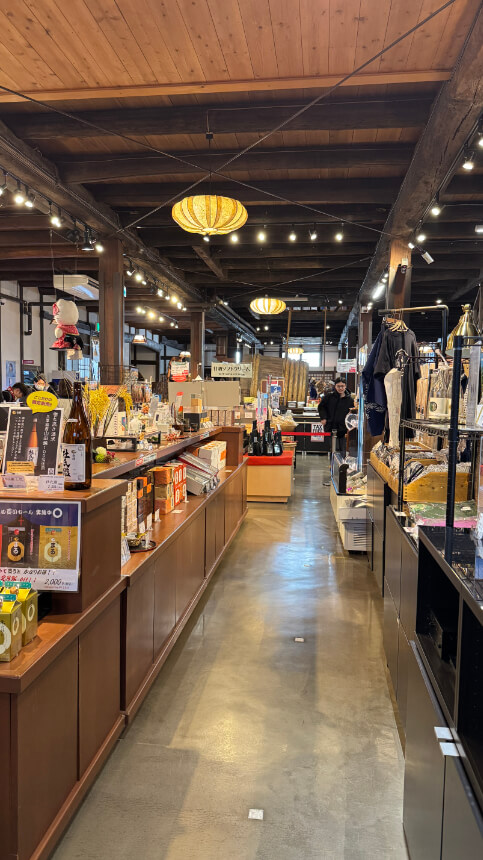 Aisle in museum gift shop, featuring sake bottles, souvenirs, and local products