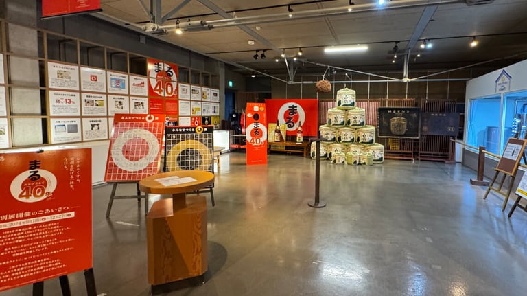 Display room featuring sake barrels, modern advertising panels, and informational exhibits about sake production