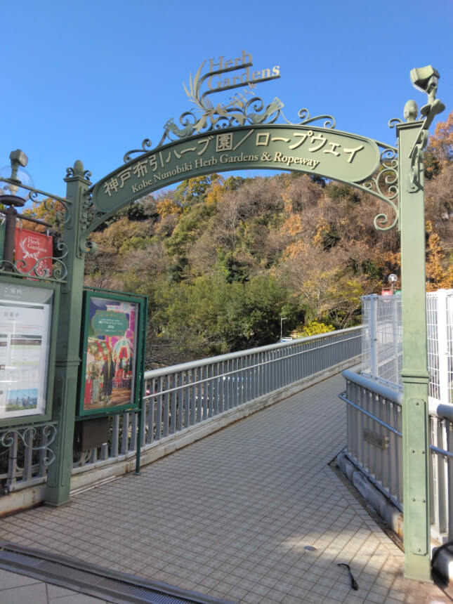Entrance to Kobe Nunobiki Herb Gardens & Ropeway, featuring a decorative green archway and a tiled pathway by Shin-Kove Station. Entrance to Kobe Nunobiki Herb Gardens & Ropeway, featuring a decorative green archway and a tiled pathway by Shin-Kove Station.