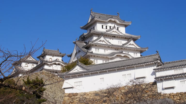 Close-up view of the main keep, showcasing its white plaster walls, tiled roofs, and stone base from just inside the paid area. Close-up view of the main keep, showcasing its white plaster walls, tiled roofs, and stone base from just inside the paid area.