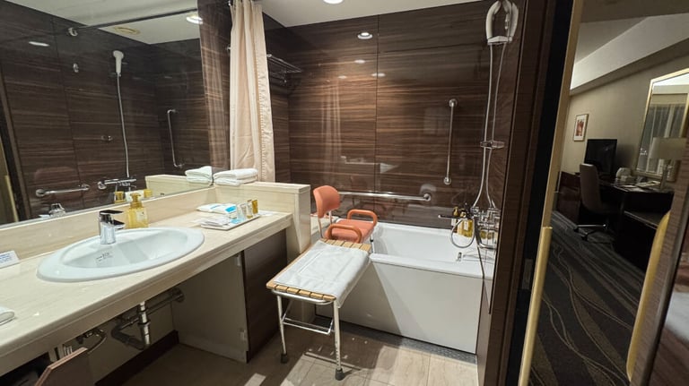The accessible bathroom features a sink, a bathtub with grab bars, a handheld shower, a transfer bench and a shower chair with a backrest.