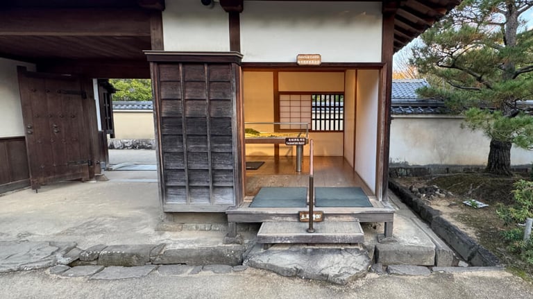 An entrance to an exhibition room with wooden flooring, accessed by three steps. A handrail is provided for support.