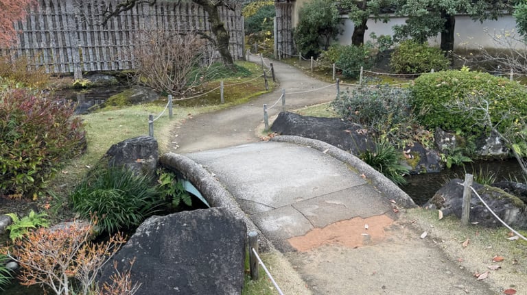 A small arched stone bridge over a stream does not have hand rails.
