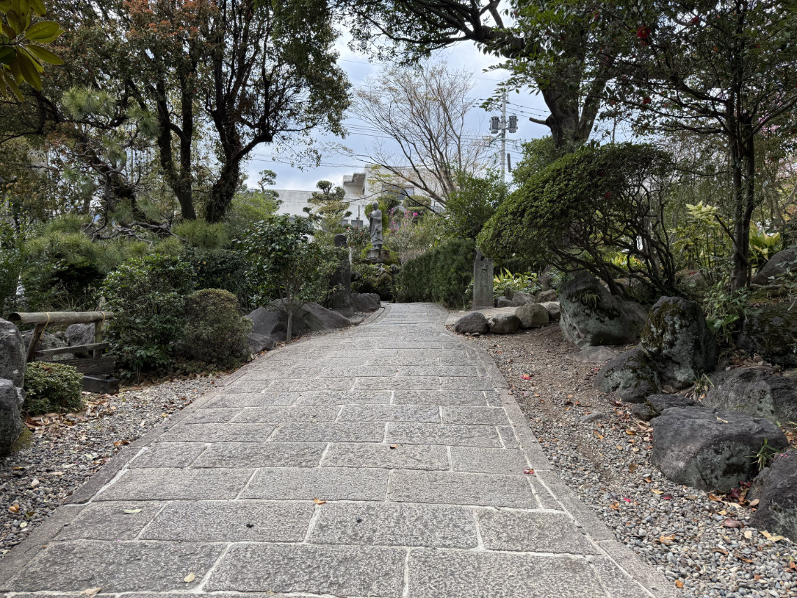 Steep stone path at Shiraike lined with trees; surface may be bumpy and challenging for wheelchair users.