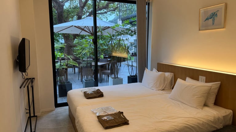 Twin bed guest room with patio access, glass sliding doors, greenery outside.