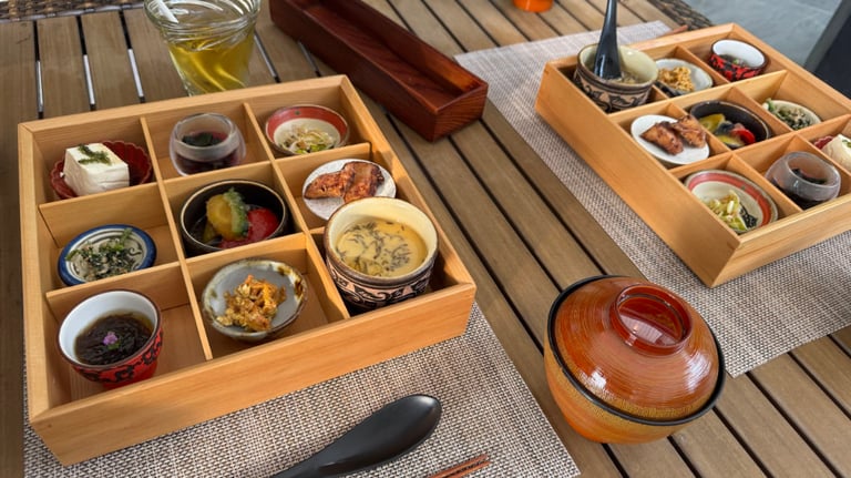Traditional Japanese meal served in wooden bento trays, featuring assorted small dishes and a miso soup bowl on a wooden table.