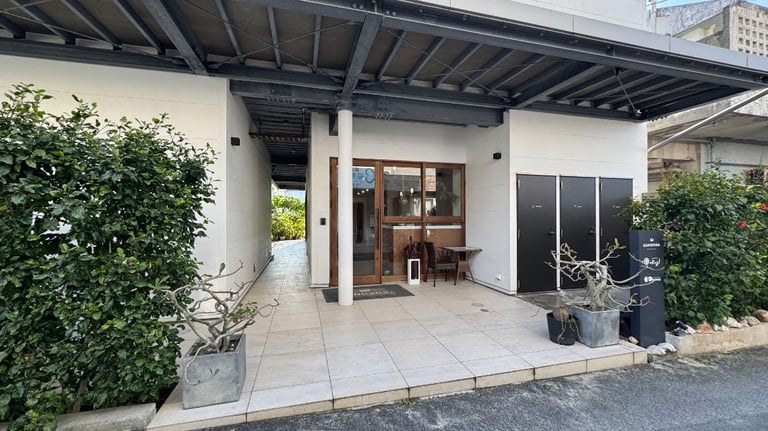 Hotel entrance with a small single step, glass entry doors, and black doors to shared shower and toilet facilities on the right.