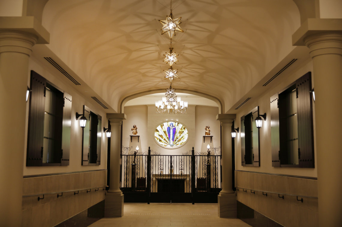 Elegant hallway with star-shaped lights, stained glass, and wrought iron gate at Hotel Monterey Himeji’s chapel interior.