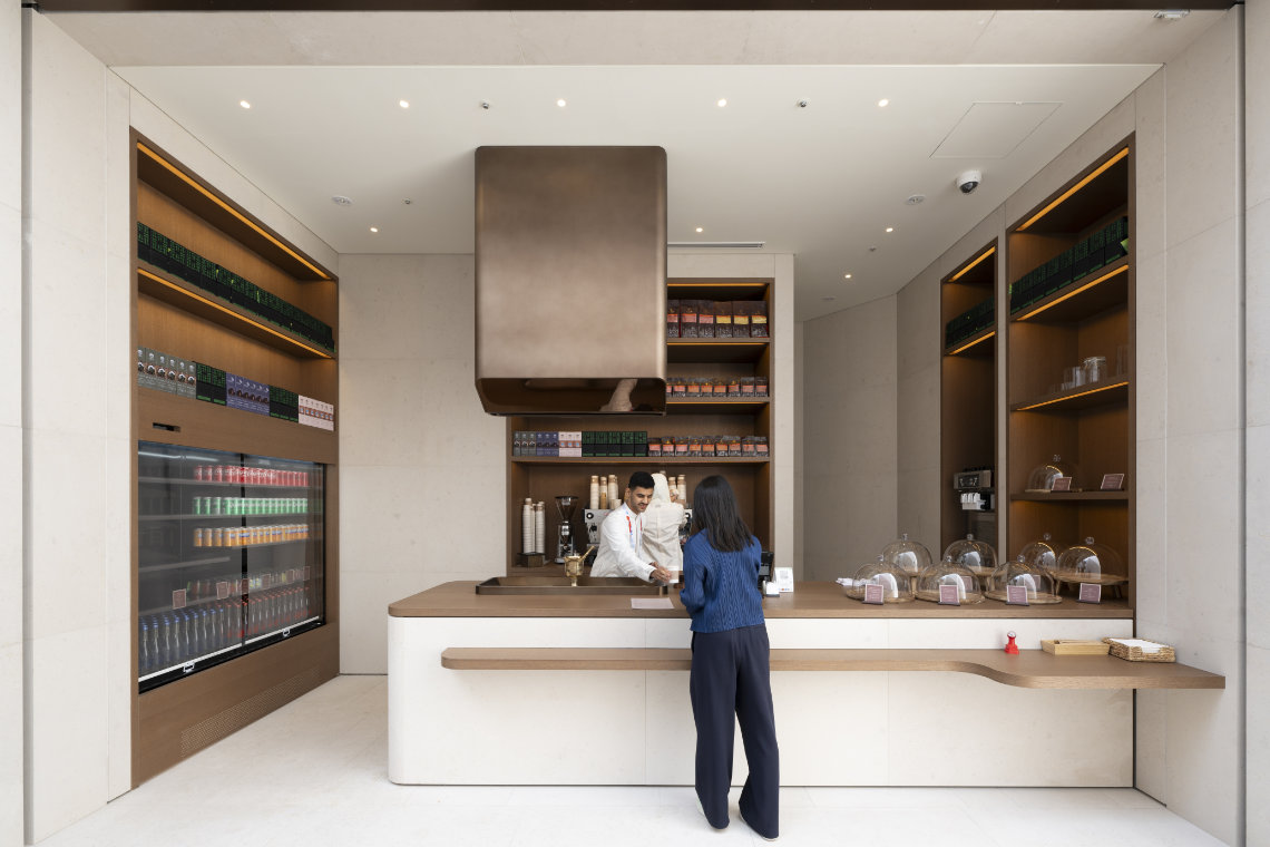 A visitor orders a drink at a sleek modern café counter inside the Saudi Arabia Pavilion at Expo 2025.