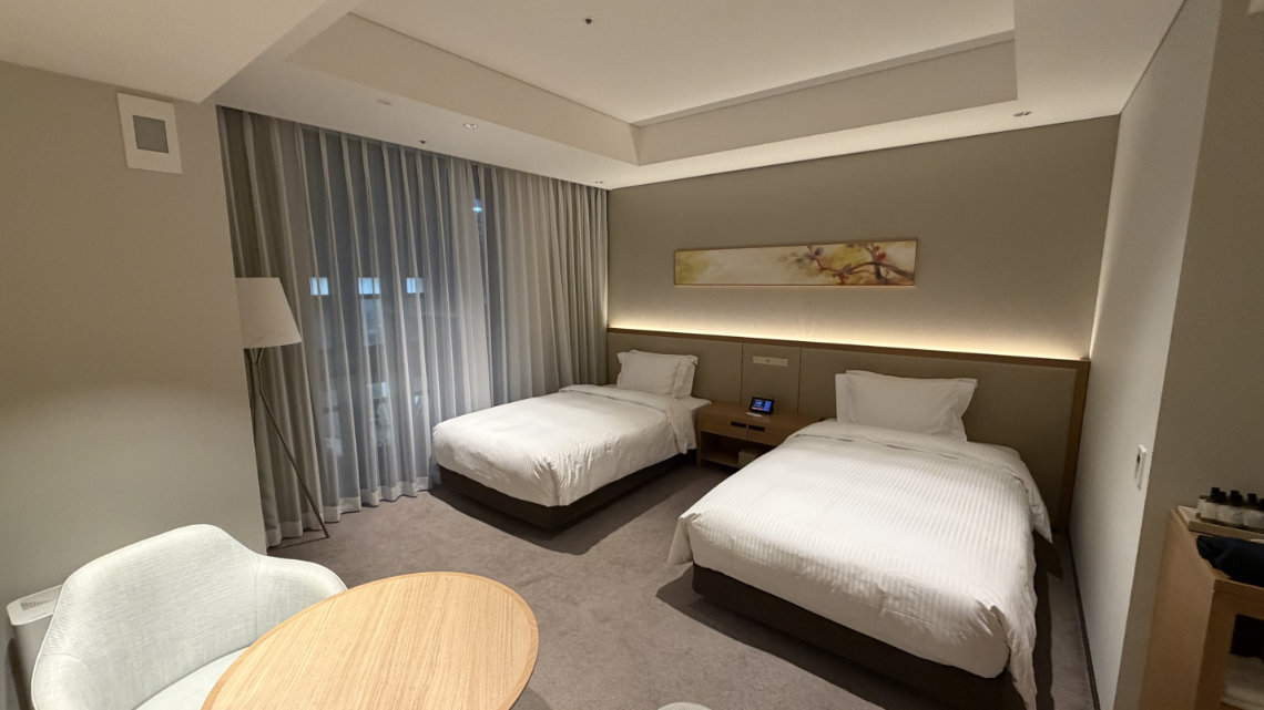 Accessible room at Miyako Hotel Hakata with two single beds, a round table, and floor-to-ceiling curtains in a modern setting.