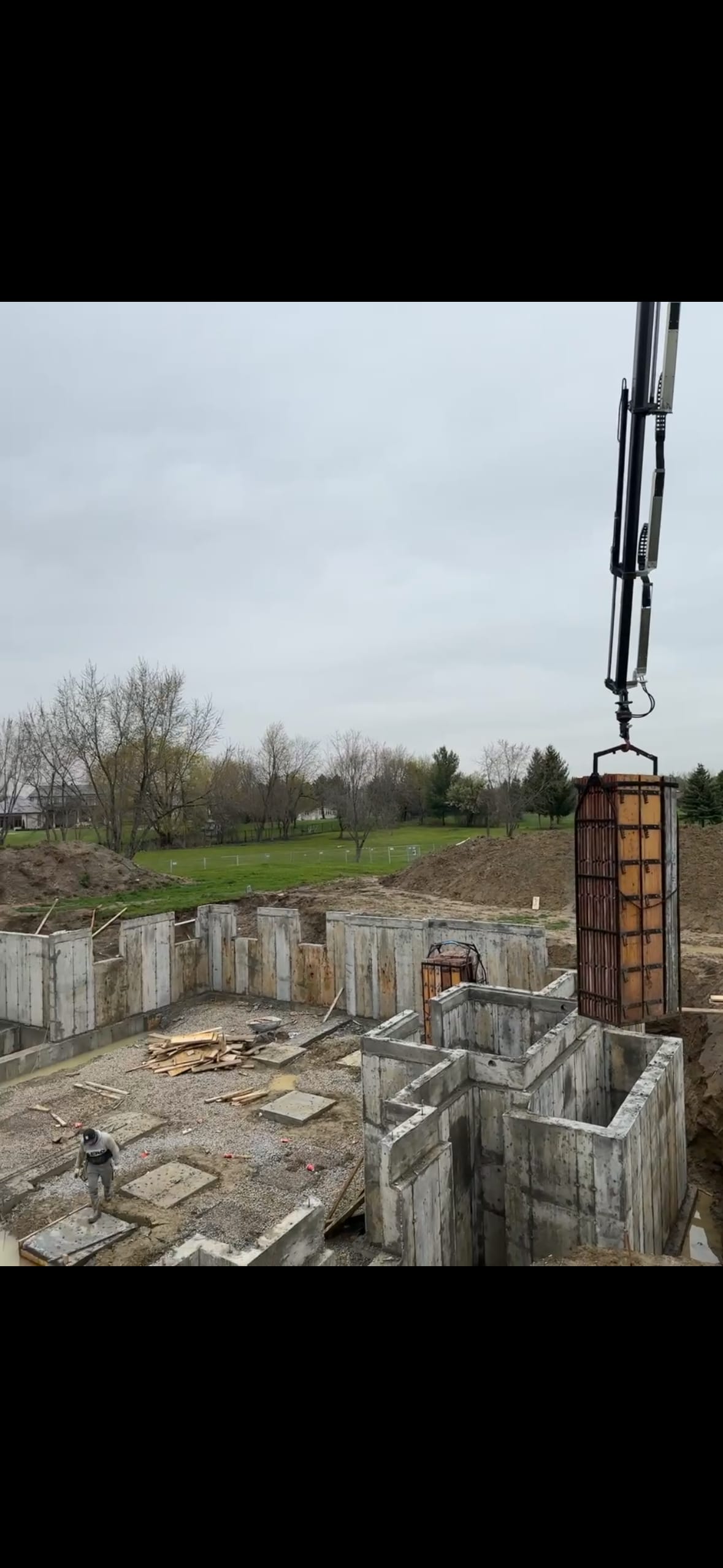 Freshly stripped concrete foundation walls in Brampton with rebar cages being crane-lifted for installation