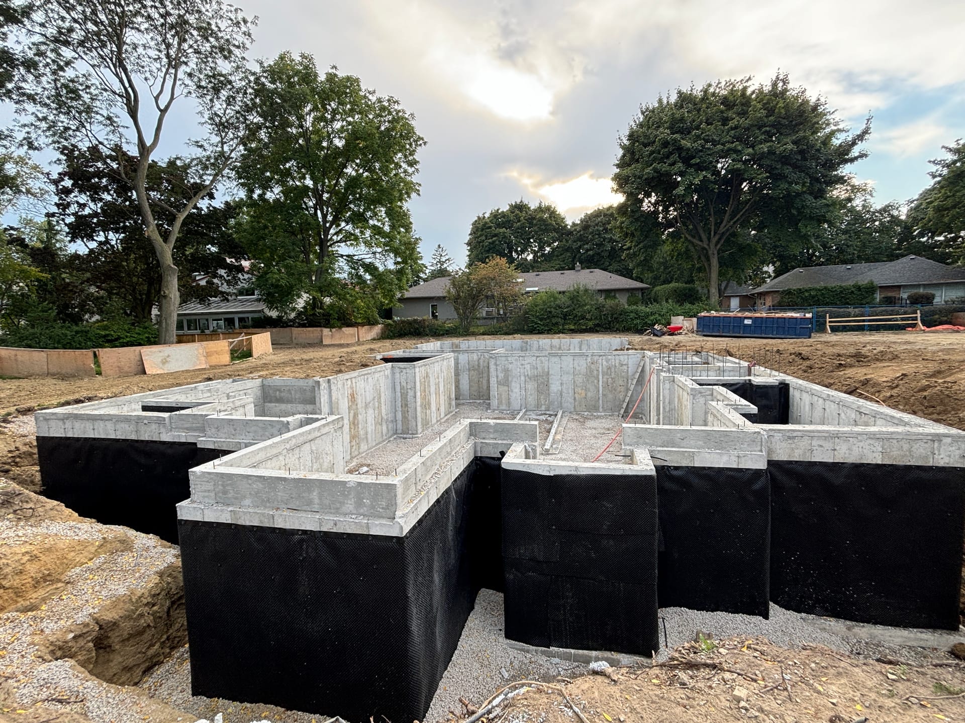 Freshly stripped concrete foundation walls with formwork removal underway in Etobicoke residential construction project