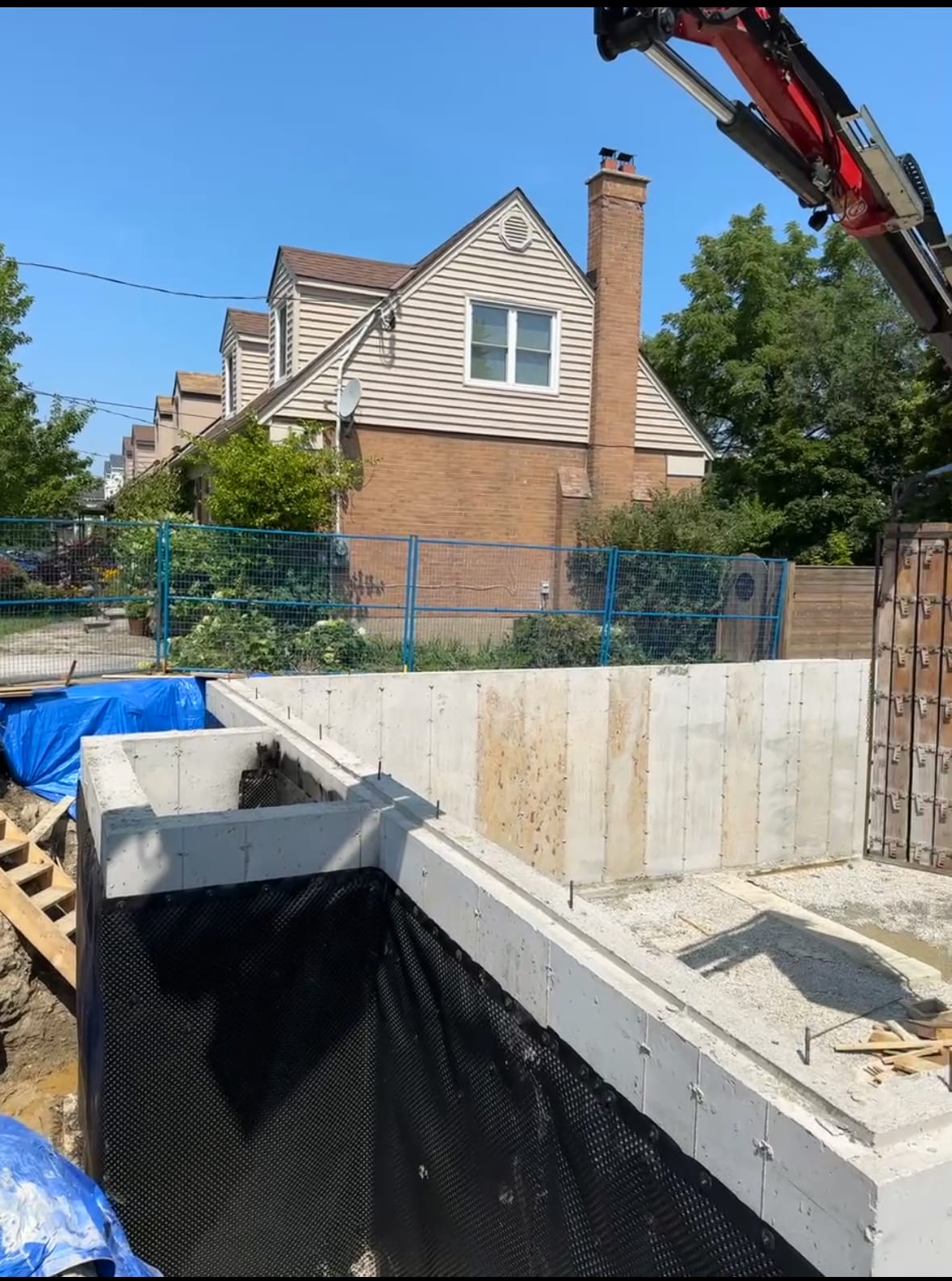 Completed foundation with waterproofing in Etobicoke showing crane lifting formwork cages from site