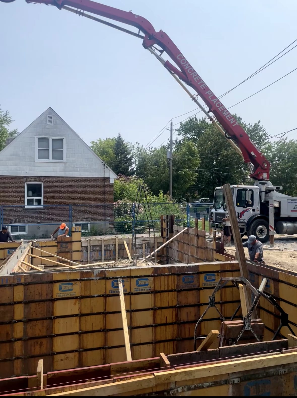 Concrete pump truck pouring foundation walls at Etobicoke residential site with braced formwork