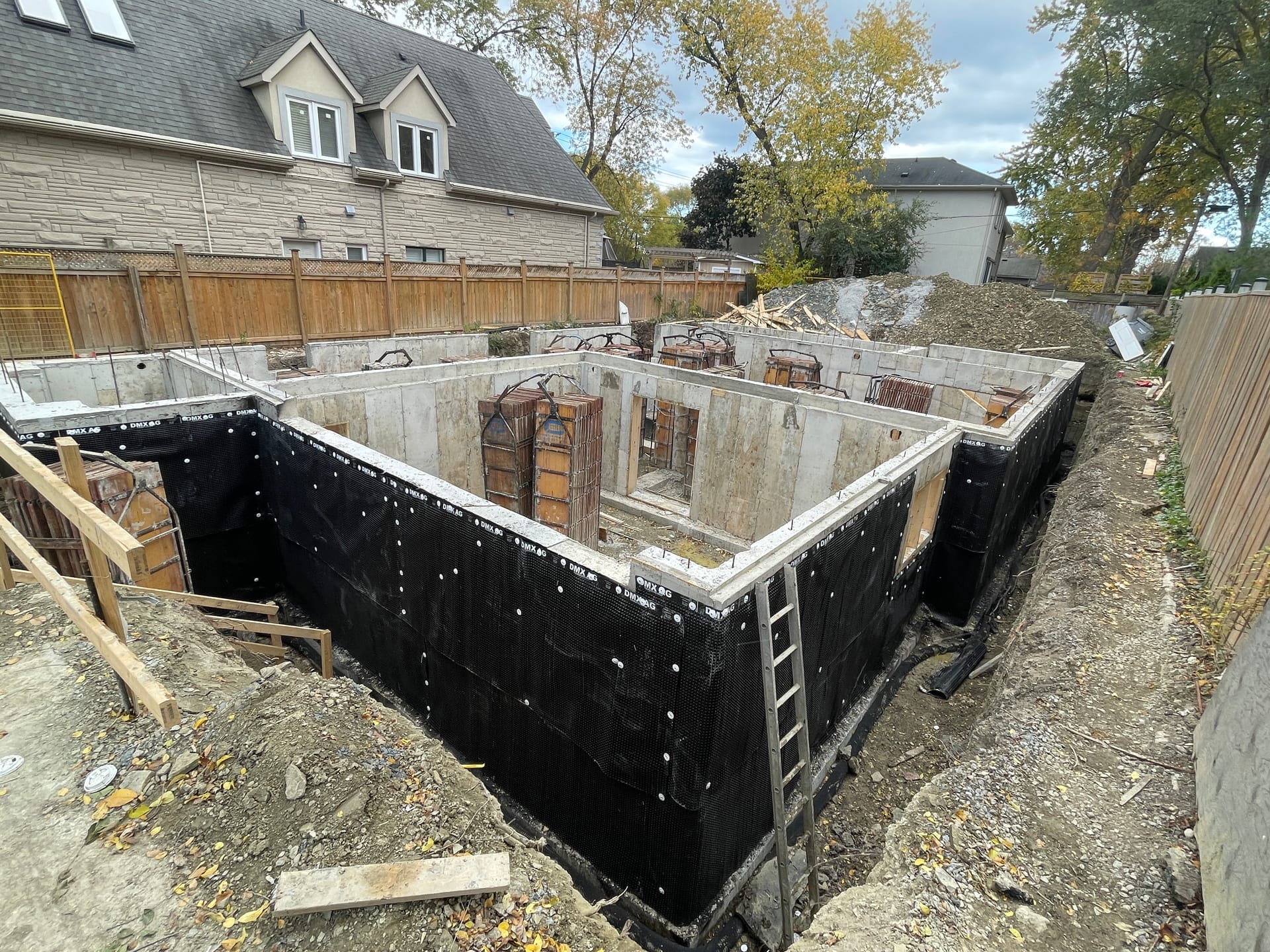 Foundation waterproofing and rebar cages awaiting crane removal at Mississauga residential construction site