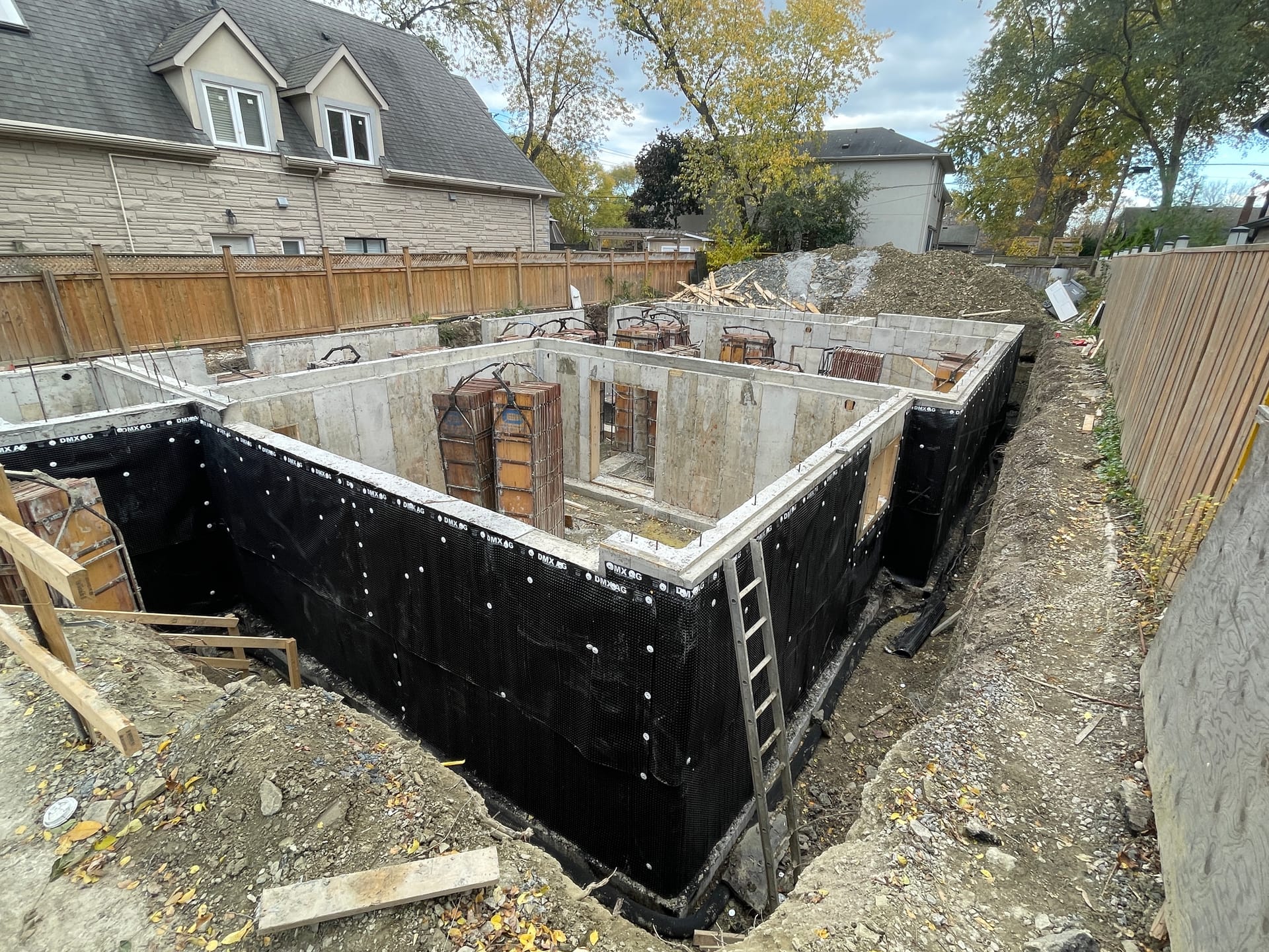 Waterproofed foundation walls ready for backfill at Mississauga custom home construction project