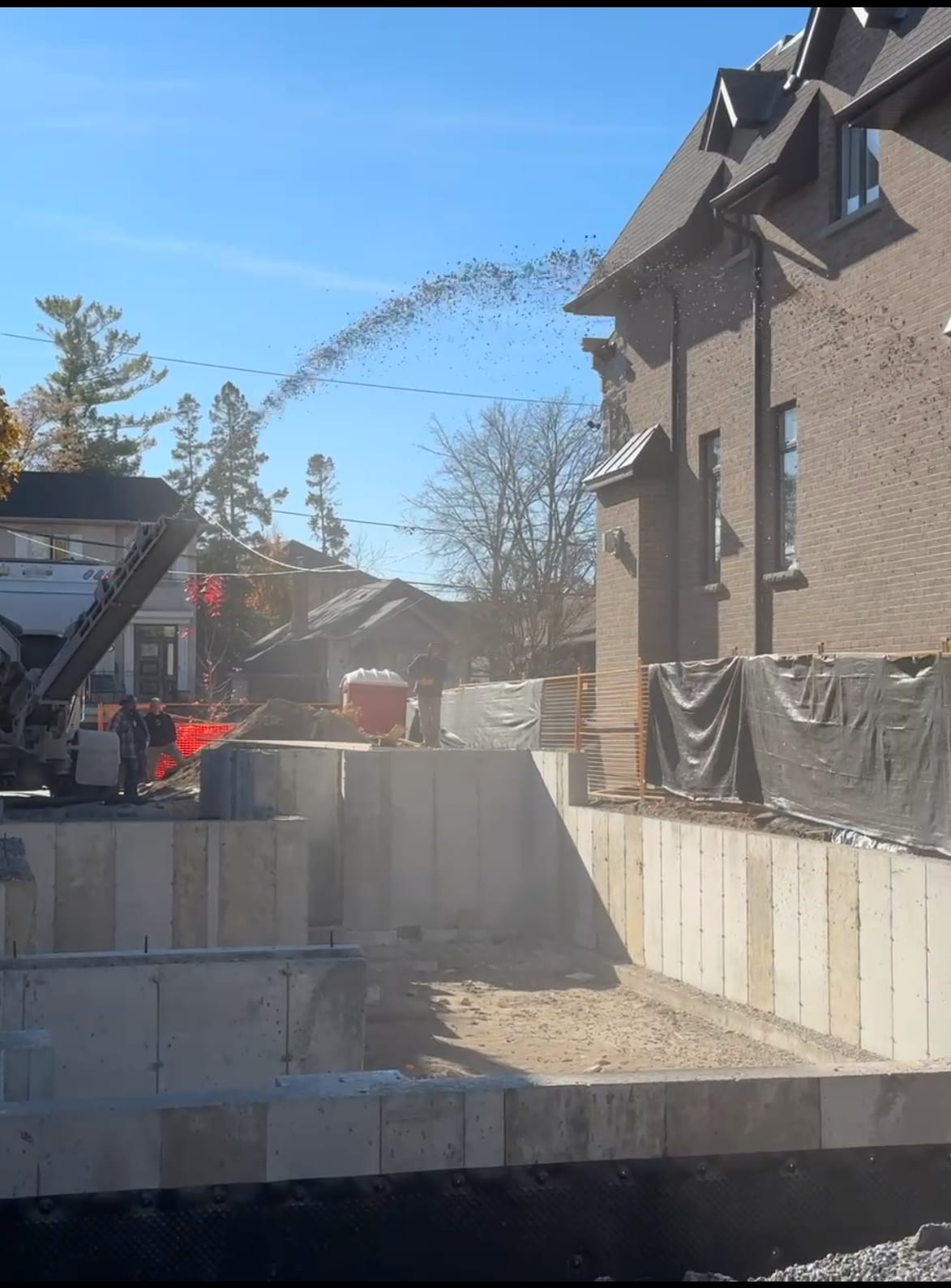 Concrete pump hovering over braced foundation walls during pour in North York