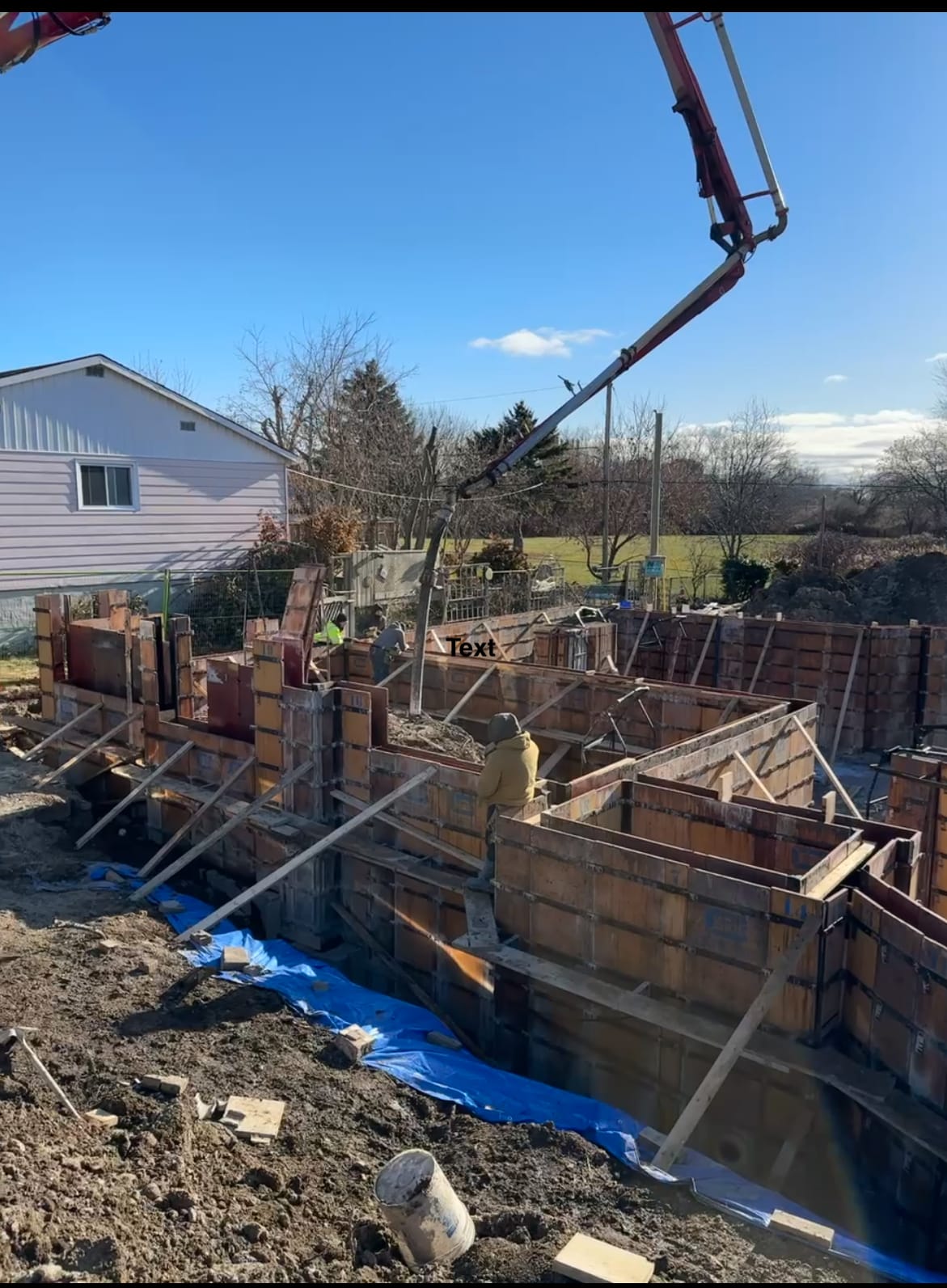 Concrete pump delivering material to assembled wall formwork during pour in Pickering