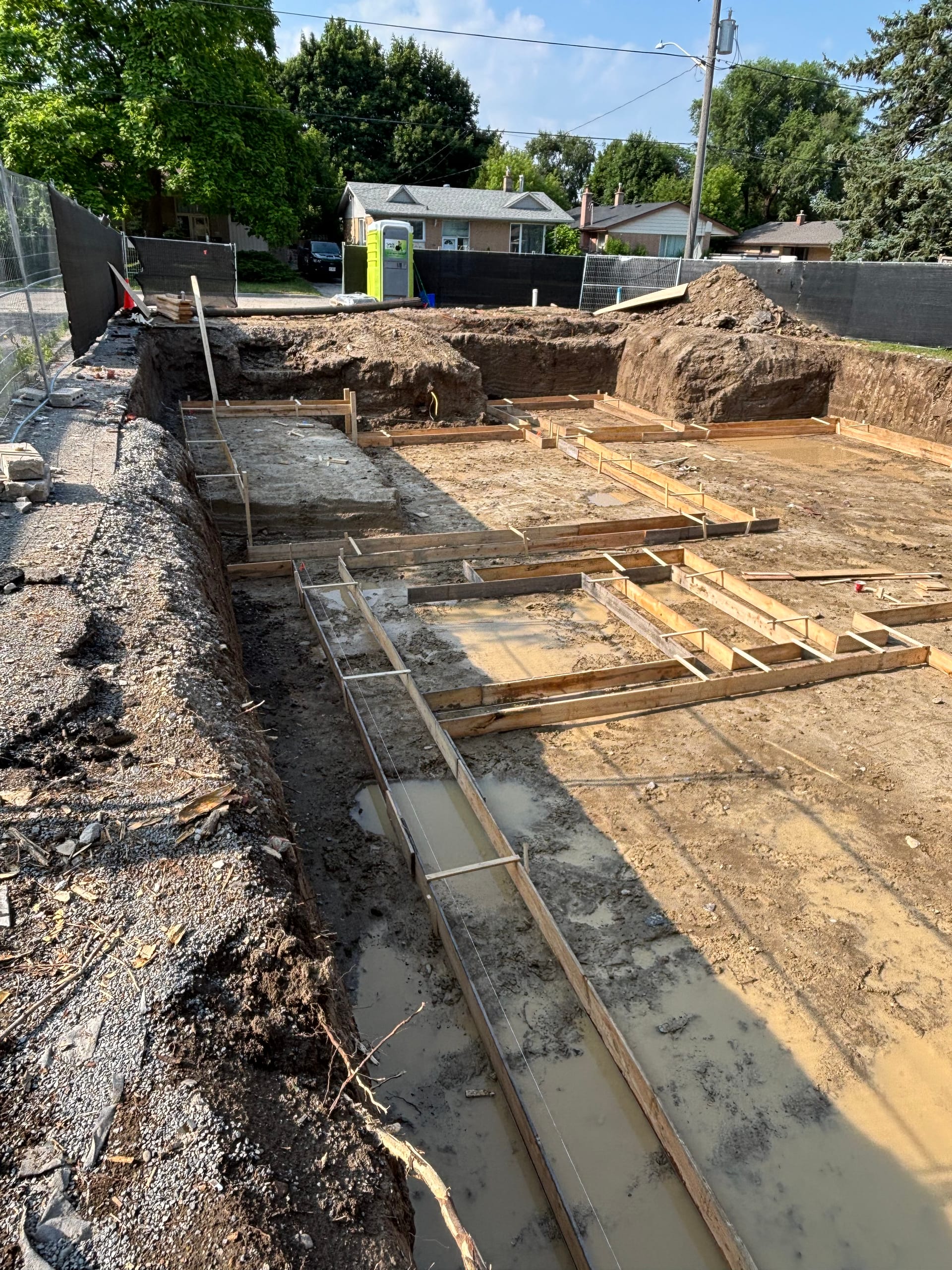 Black cement waterproofing membrane application on Richmond Hill foundation walls with wooden bracing