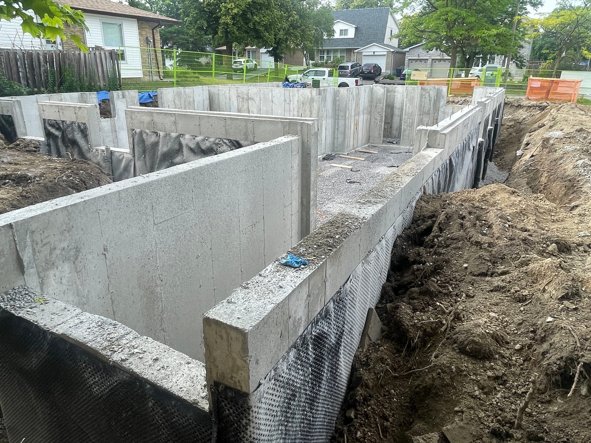Completed foundation in Scarborough with waterproofing applied and backfill underway at residential construction site