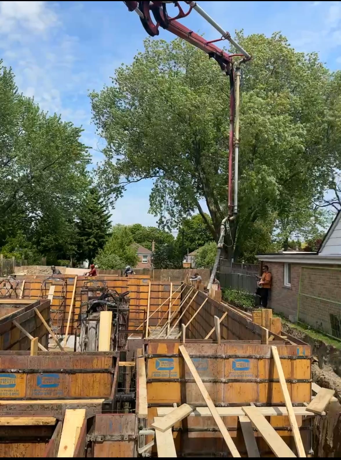 Crane lowering wall formwork cages with weeping tile installation at Scarborough foundation site