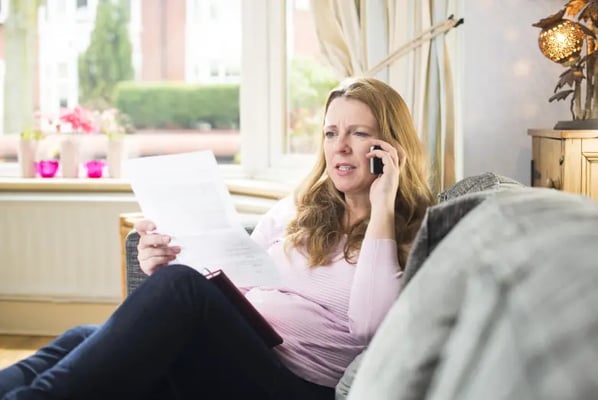 Woman on sofa reading a conditional fee agreement