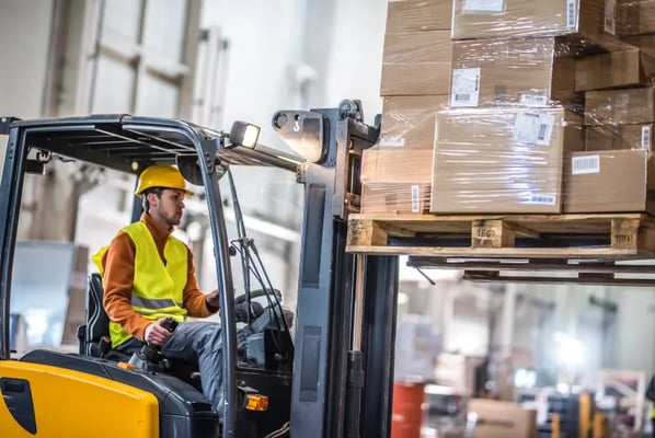 Forklift truck and driver being operated in a warehouse aisle