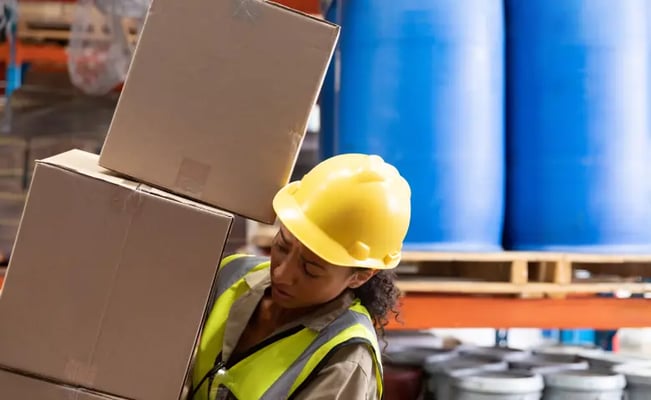 Woman at work carrying boxes falling on her