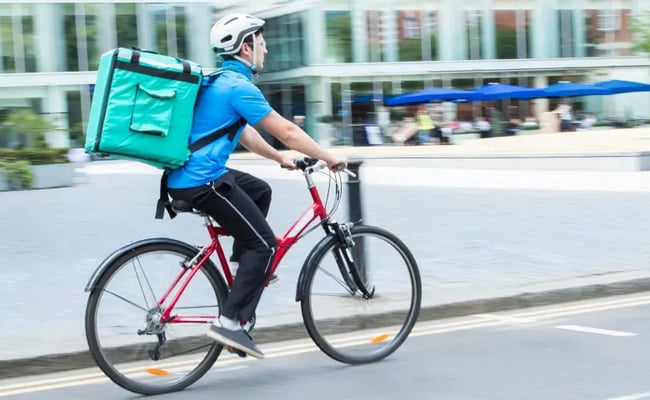 Male zero hours contract food delivery rider on his bicycle
