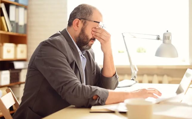 Worried and injured man sitting at his desk