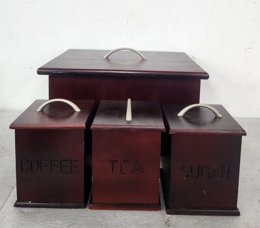 A set of three vintage dark wood kitchen canisters and a matching large bread box or storage bin.