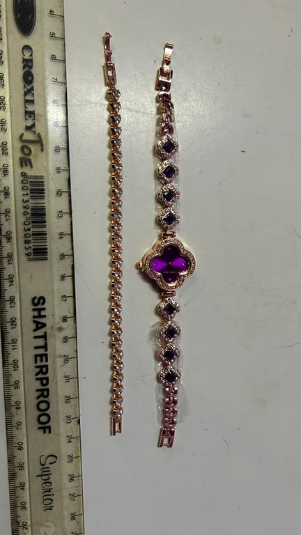 Rose gold toned quartz watch features a clover shaped case with purple accents and matching clover link bracelet