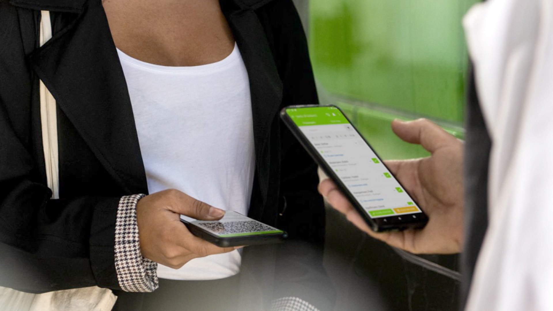 A FlixBus passenger showing a mobile ticket to staff, who check it on a smartphone before boarding.