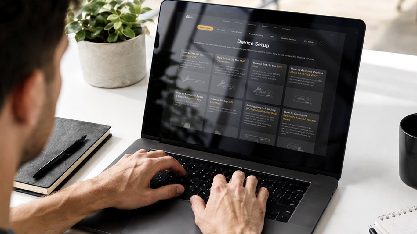 Laptop on a desk displaying the Peplink Device Setup how-to page