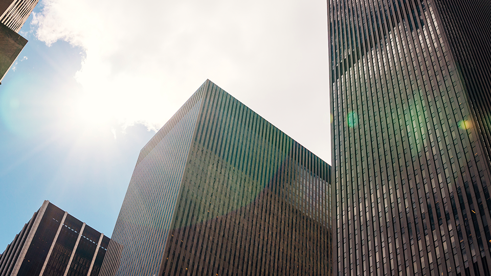 Low-angle view of enterprise office skyscrapers against a bright sky.