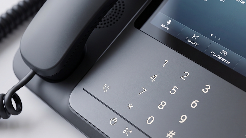 Close-up of a VoIP desk phone with keypad and call transfer controls.