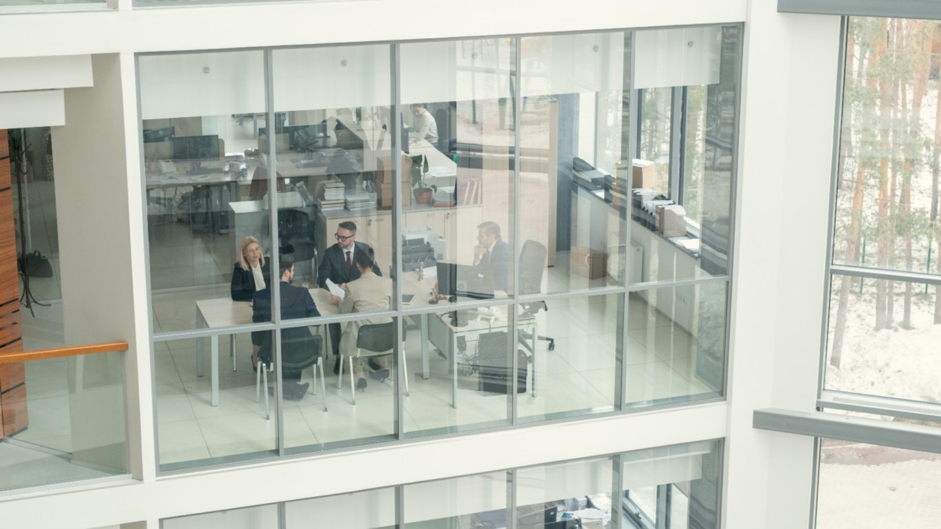 Business meeting in a glass-walled office representing Peplink finance case studies.