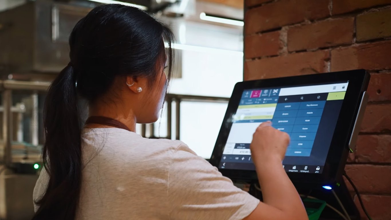Retail staff using a touchscreen POS system in a store representing Peplink retail case studies.