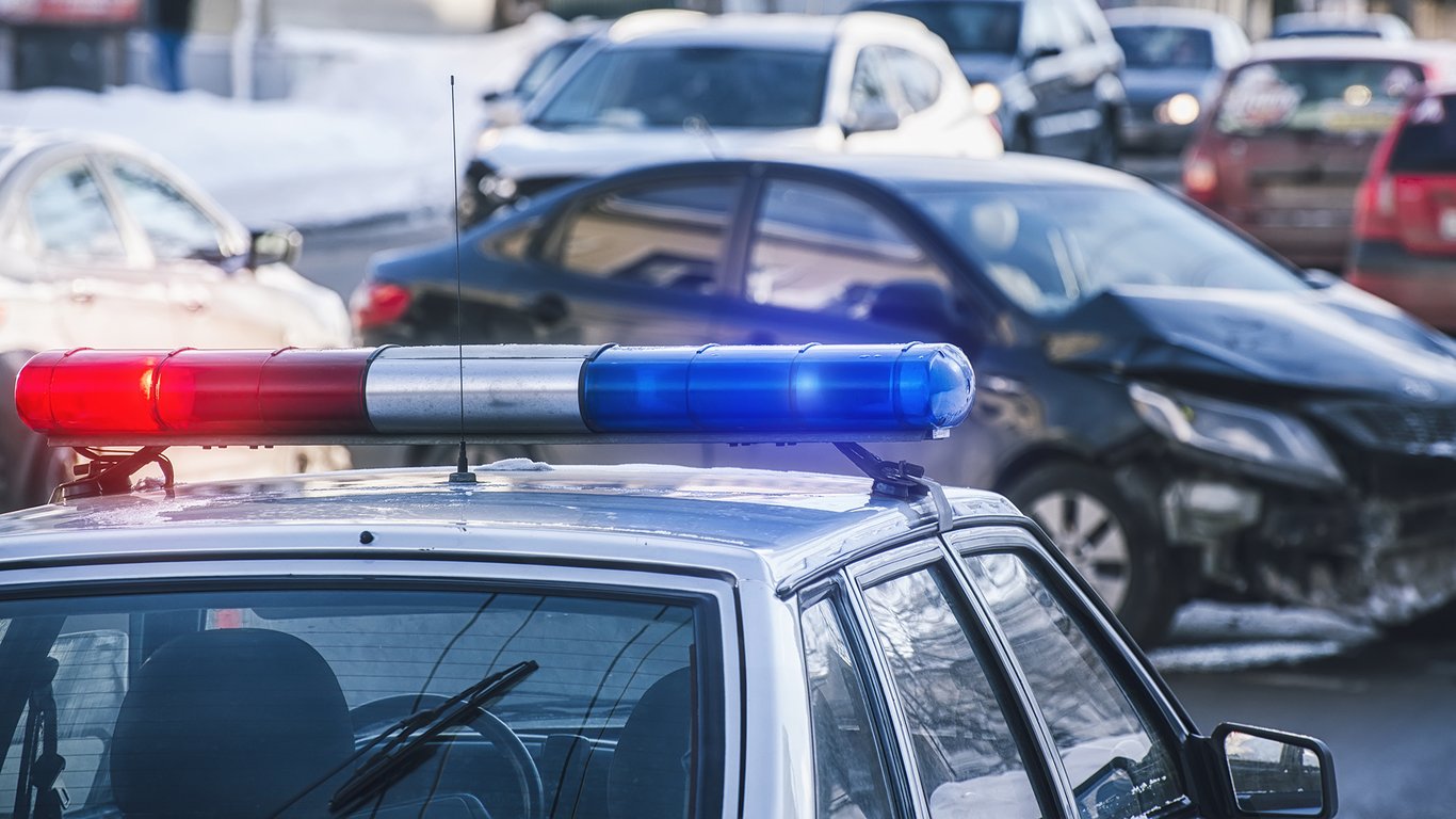 Police vehicle with active emergency lights at a road incident representing Peplink public safety connectivity.