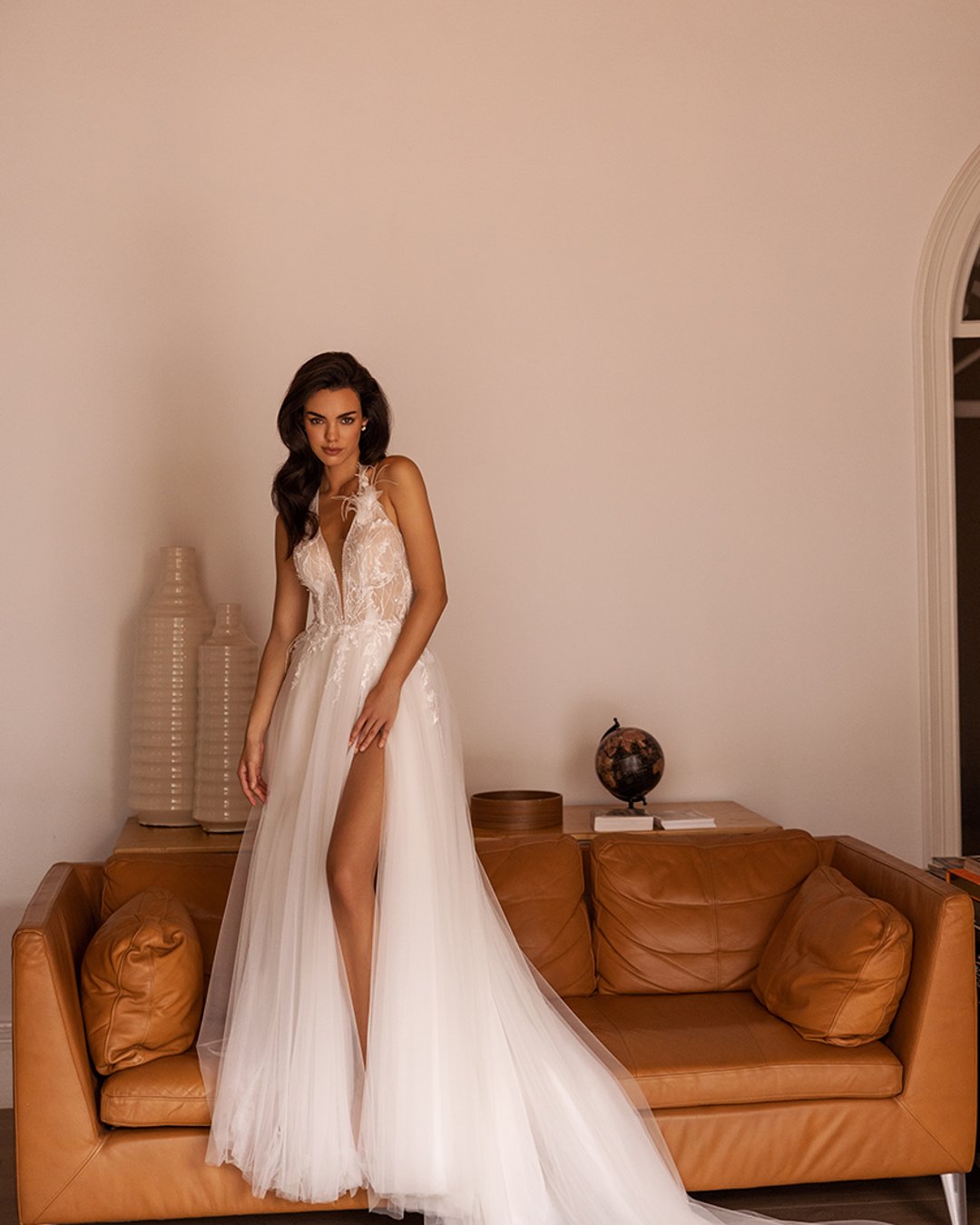 Suknia Elizabeth Passion o linii A z głębokim dekoltem, koronkowymi detalami, piórami oraz efektownym rozcięciem na nogę. Z tyłu zapinana na szyję, idealnie podkreślająca sylwetkę.