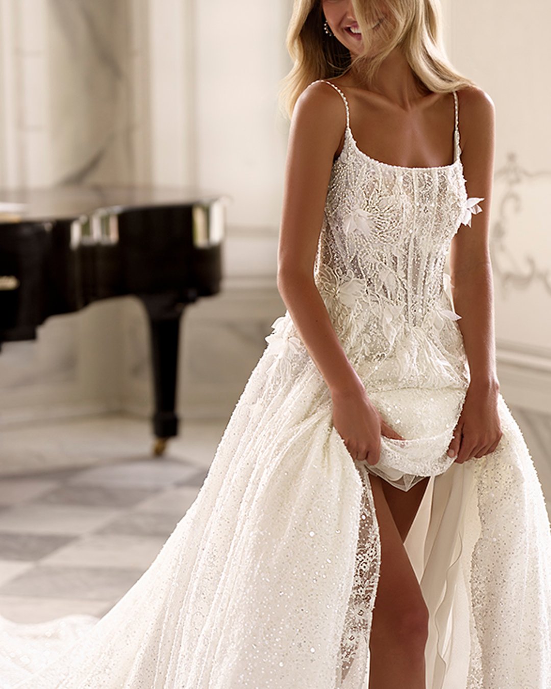 Suknia ślubna Kupelius to olśniewająca princessa z szeroką, błyszczącą spódnicą, zdobiona perełkami i koronką. Na cienkich ramiączkach, z prostym dekoltem i delikatnie prześwitującą górą – elegancja w najczystszej formie.